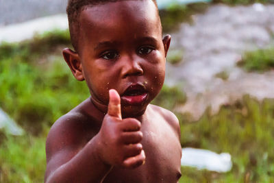 Portrait of shirtless boy holding baby outdoors