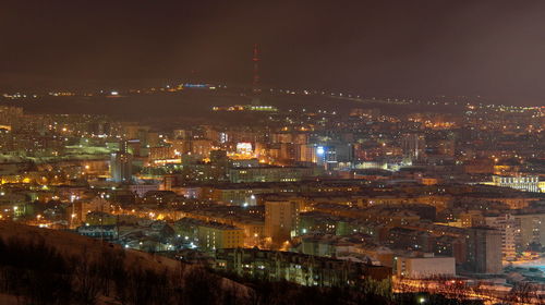 Illuminated cityscape against sky at night