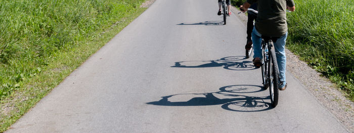 Bicycle shadow silhouettes roll along a road 