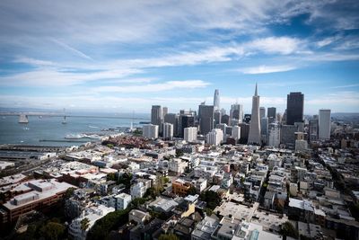 Aerial view of cityscape against cloudy sky