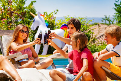 Friends using mobile phone while sitting on sofa at park