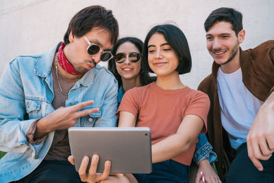 Woman taking selfie with friends against wall