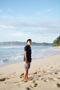 Full length of man standing on beach against sky