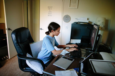 Side view of man using mobile phone while sitting on table