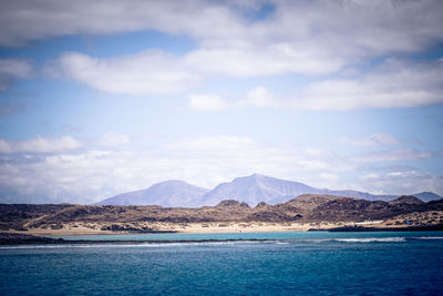 Scenic view of sea and mountains against sky