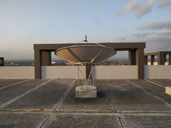 Metallic structure by building against sky during sunset