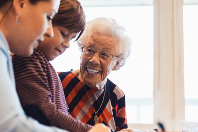 Happy senior woman looking at great grandson and daughter at home