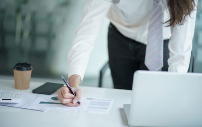 Midsection of businesswoman working at table