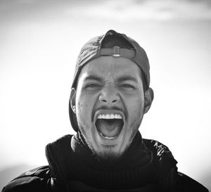 Portrait of young man screaming against sky