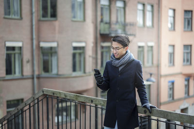 Handsome man with smartphone on footbridge