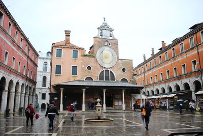 People in front of historic building against sky