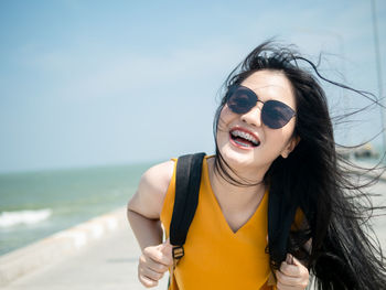 Portrait of smiling young woman wearing sunglasses at beach