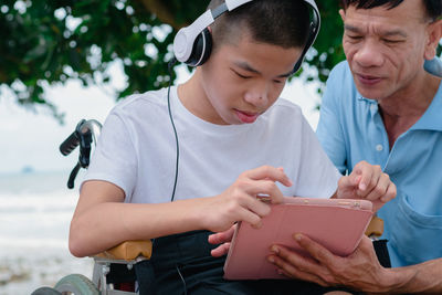 Boy listening music while sing digital tablet with father