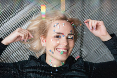 Portrait of woman with confetti on face lying on floor