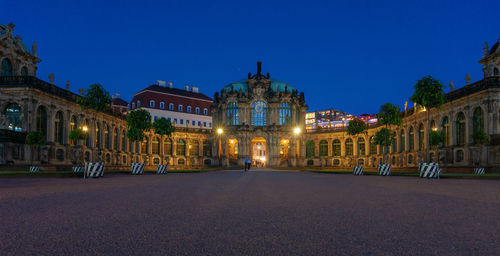 Illuminated buildings against blue sky at night