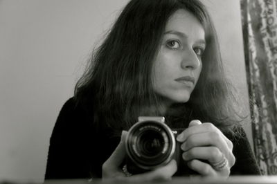 Young woman holding camera at home