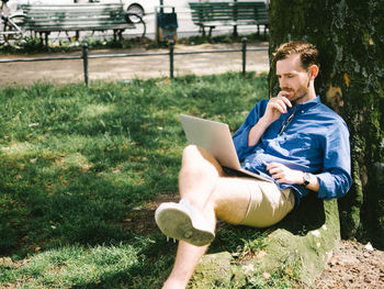 Young man using mobile phone in grass