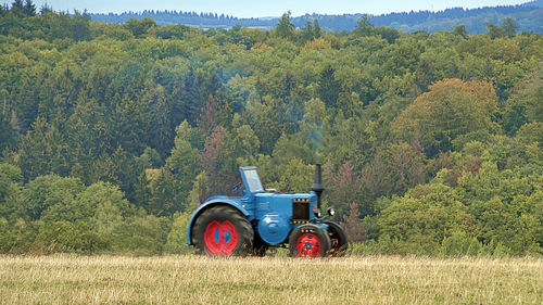 Tractor on field against trees in forest