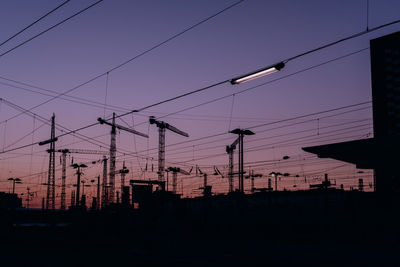 Low angle view of silhouette electricity pylon against sky at sunset