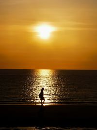 Silhouette woman walking at beach during sunset