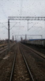 Wet railroad tracks against sky during winter