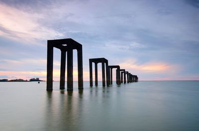 Pier over sea against sky during sunset