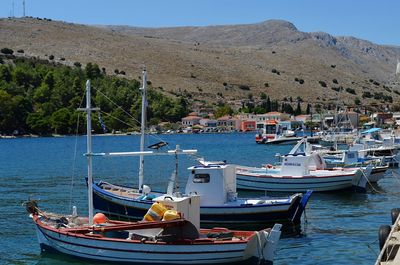 Boats moored at harbor against sky