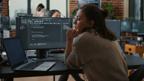 Side view of young woman using laptop at office