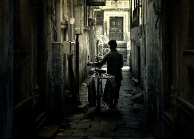 Rear view of man standing on footpath amidst buildings