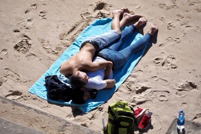 High angle view of friends relaxing on sand at beach