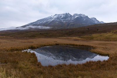 Scenic view of landscape and mountain against cloudy sky