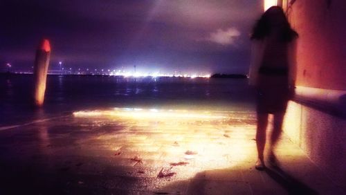 Blurred motion of person standing on beach at night