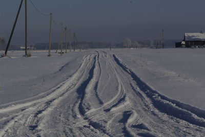 Tire tracks on snow field against sky