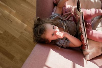 Areal view of young girl sat on a chair looking up at home reading
