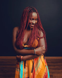 Portrait of young woman standing against black background