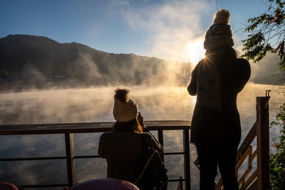 Rear view of people looking at mountains against sky