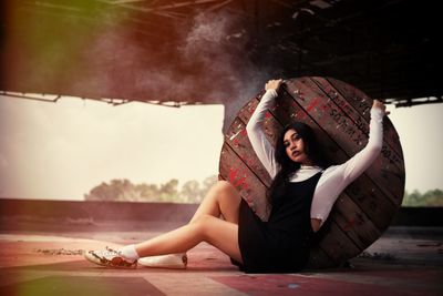 Portrait of young woman leaning on wooden table while sitting on floor