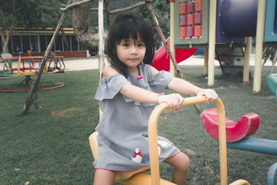 Portrait of cute girl sitting on slide at playground