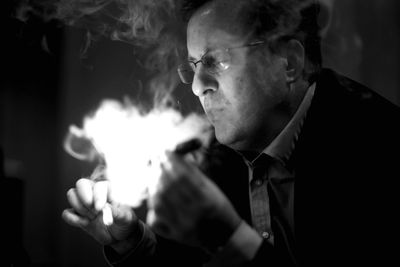 Man exhaling smoke in darkroom