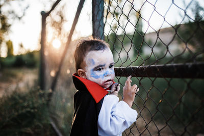 Portrait of boy looking through chainlink fence