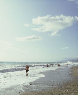 People at beach against sky