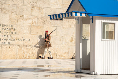 Full length of a person holding umbrella against building