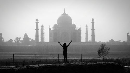 Rear view of woman standing against taj mahal in city