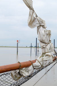 Rope tied to sailboat in river against sky