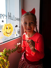 Child painting pumpkin window preparing celebrate halloween kid draws decorates room with paper bats