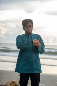 Portrait of young man standing against sky