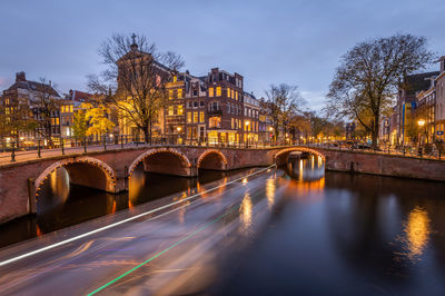 Arch bridge over river against sky in city