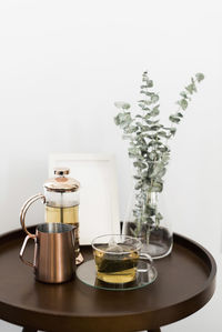 Drinks with picture frame and houseplant on table against white wall