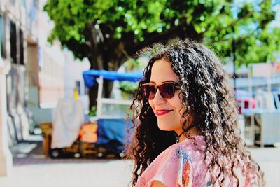 Smiling young woman wearing sunglasses on footpath