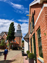 Houses by street amidst buildings in city against sky